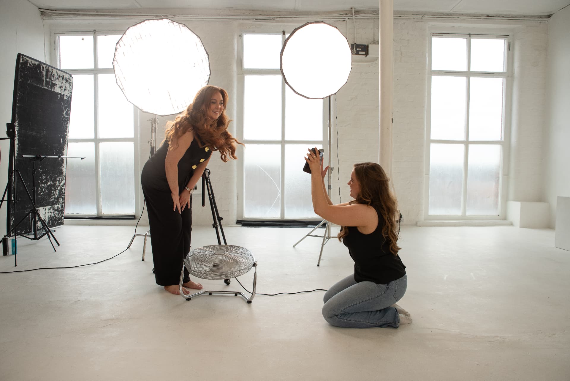 Aimee Marie Morgan directing a brand photography shoot in a bright white studio
